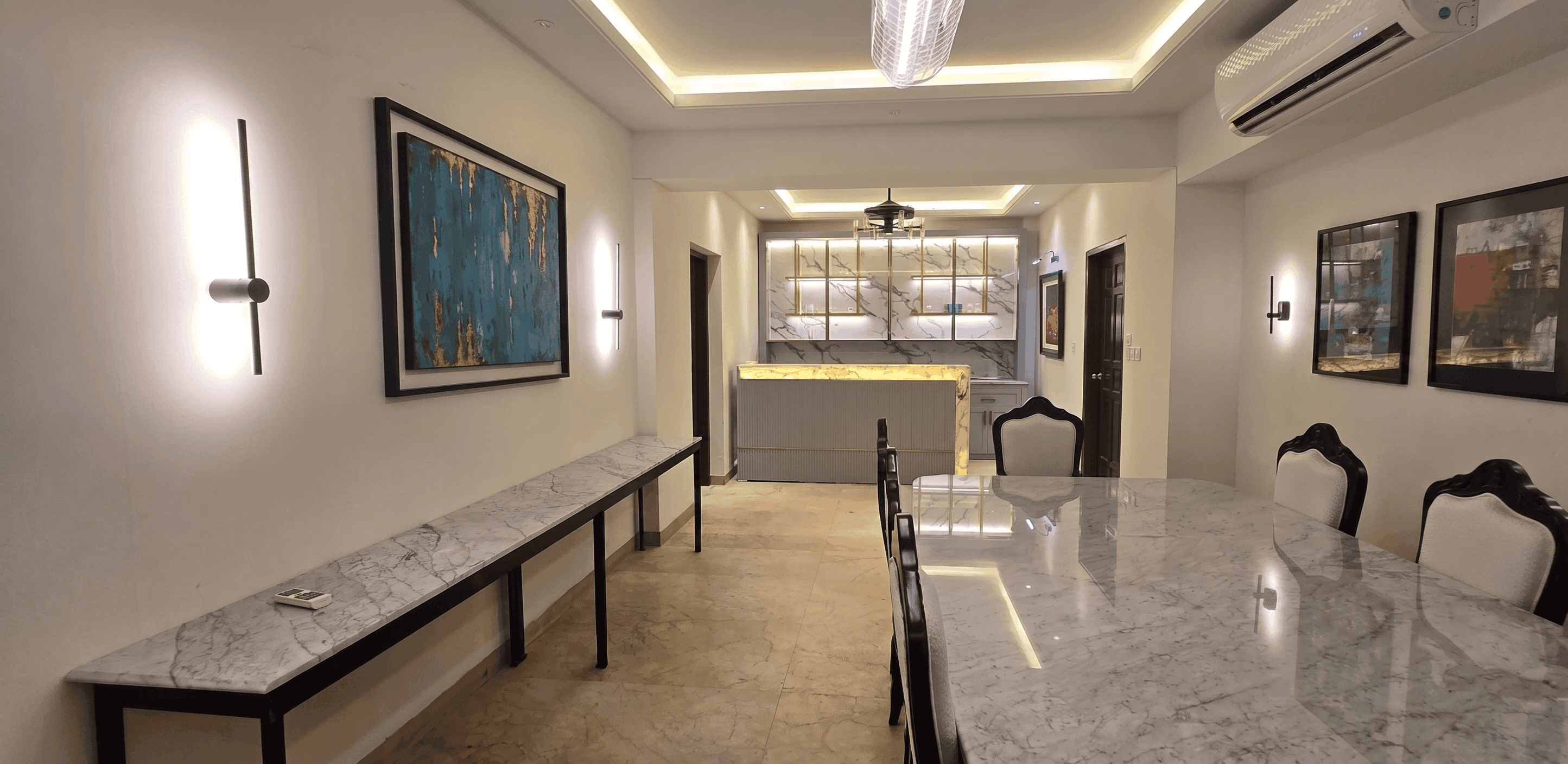 A renovated hallway: a marble console run leading to a lit onyx bar, with a cove-lit ceiling.